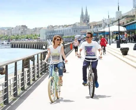 A couple ride their bikes along the Bordeaux riverfront path.