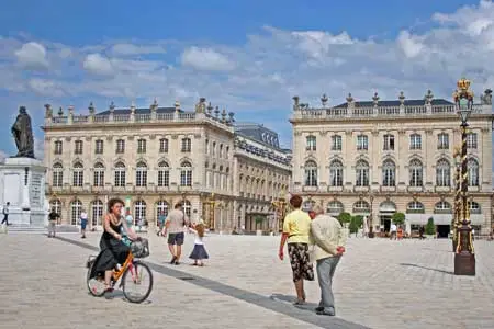 A woman riding a bike in the town center of Nancy, France.
