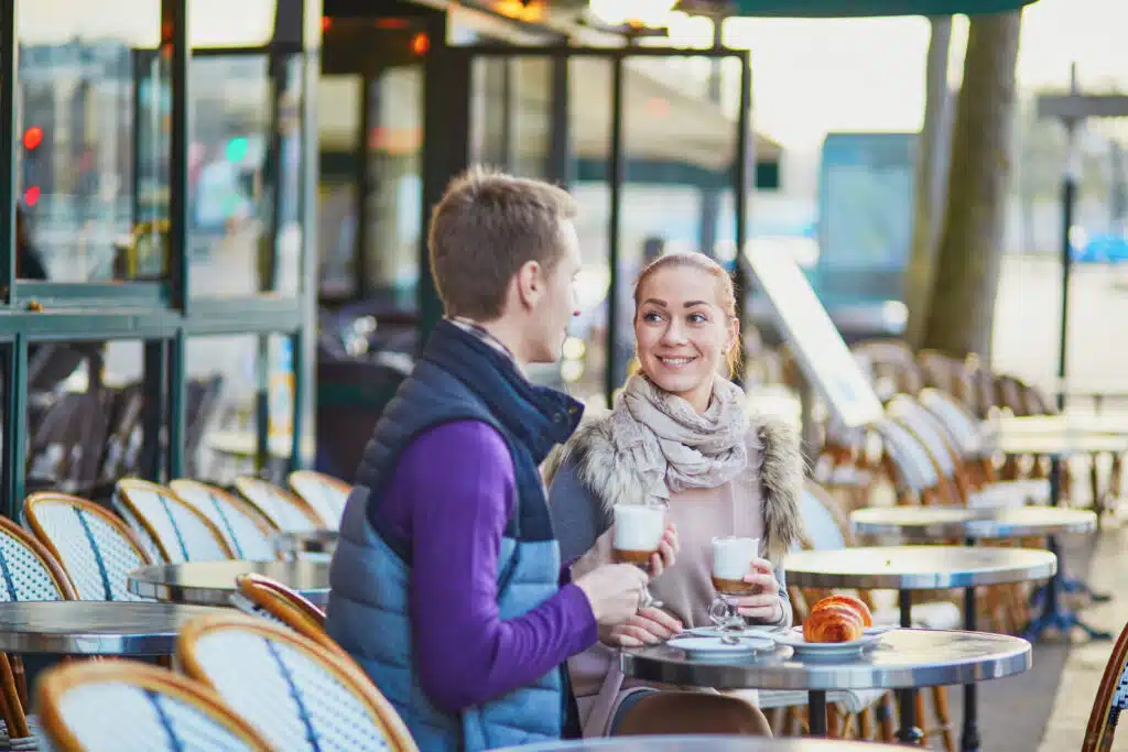 Young couple in a cafe in Paris, France enjoying coffee and a croissant.