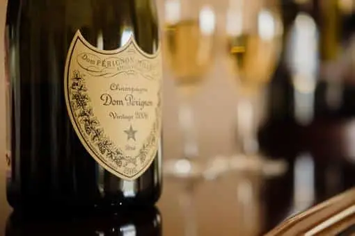 A bottle of Dom Perignon with champagne glasses in the background.
