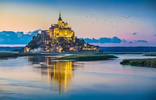 Mont St. Michel and the surrounding marshland at dusk.