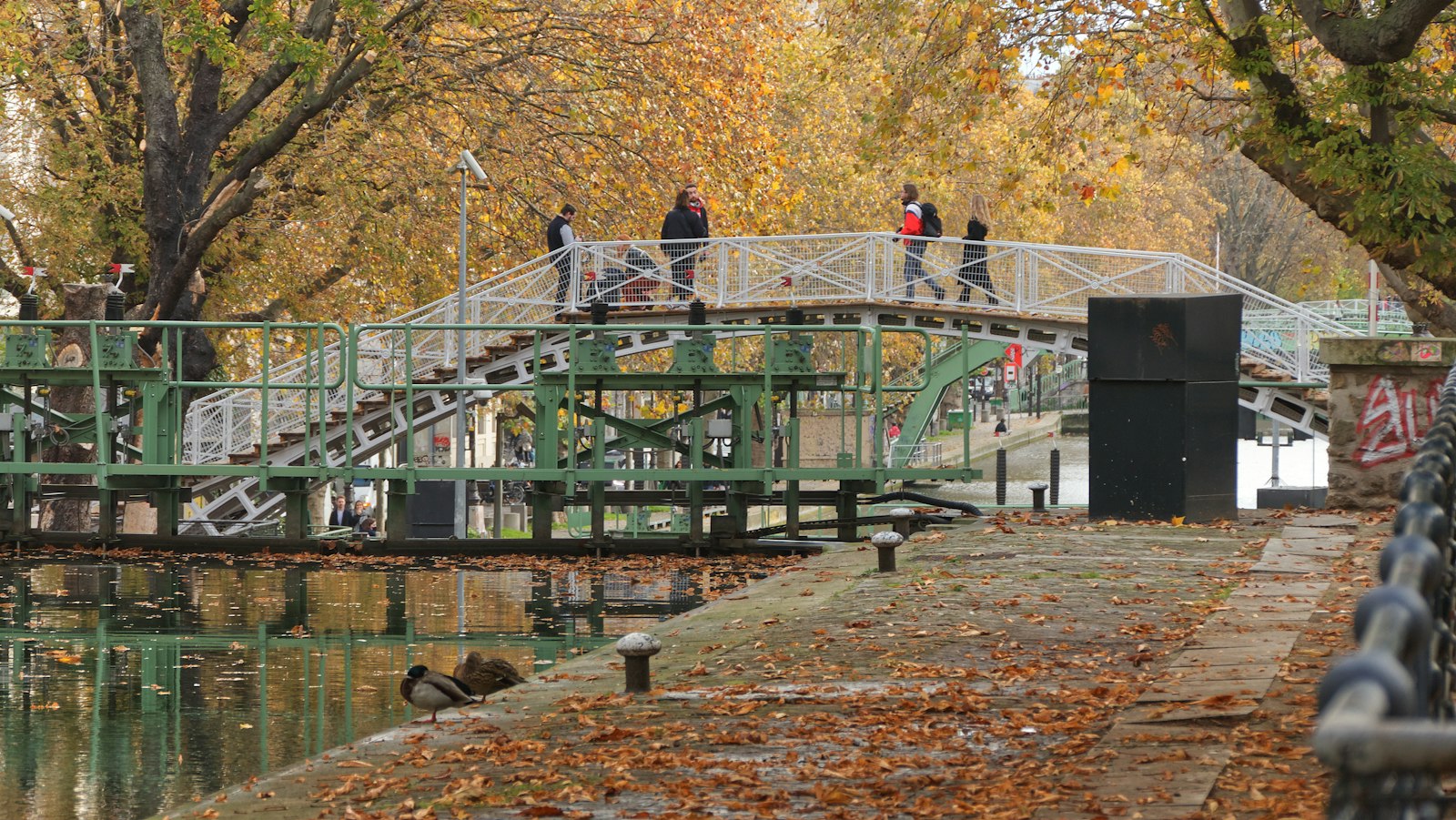 An iron footbridge and lock on the Canal Saint-Martin in autumn