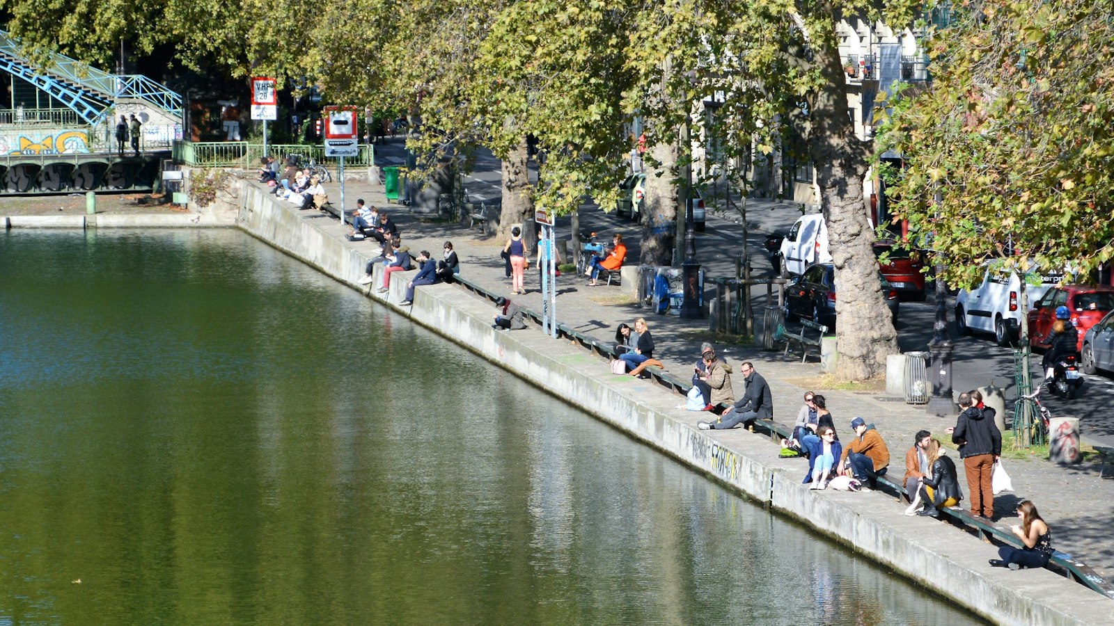 People sitting along the quay of the Canal Saint-Martin on a sunny day