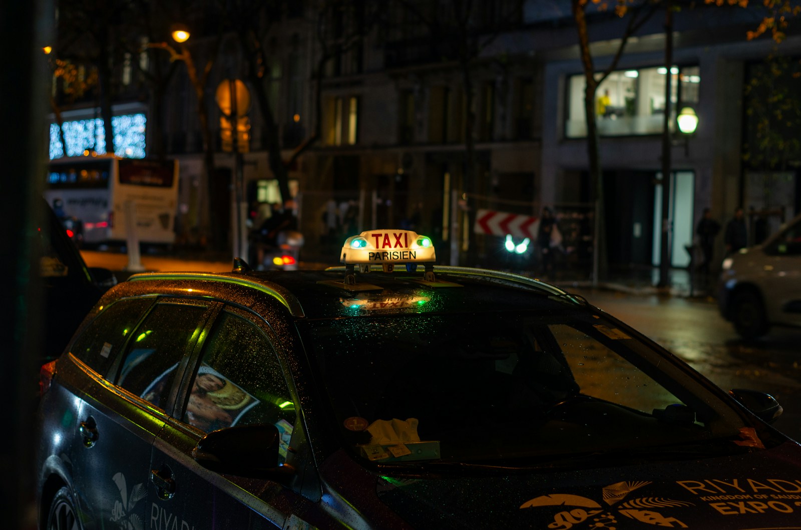 A Paris taxi with its roof light on at night